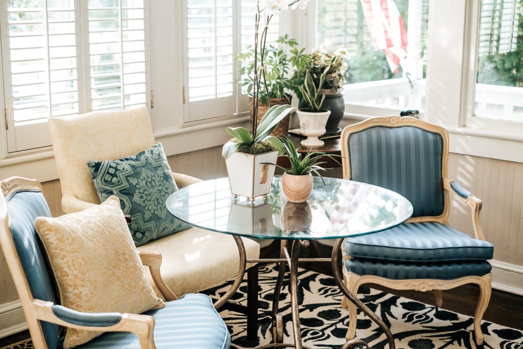 First floor sunroom featuring plants, antique chairs, and a circular glass table
