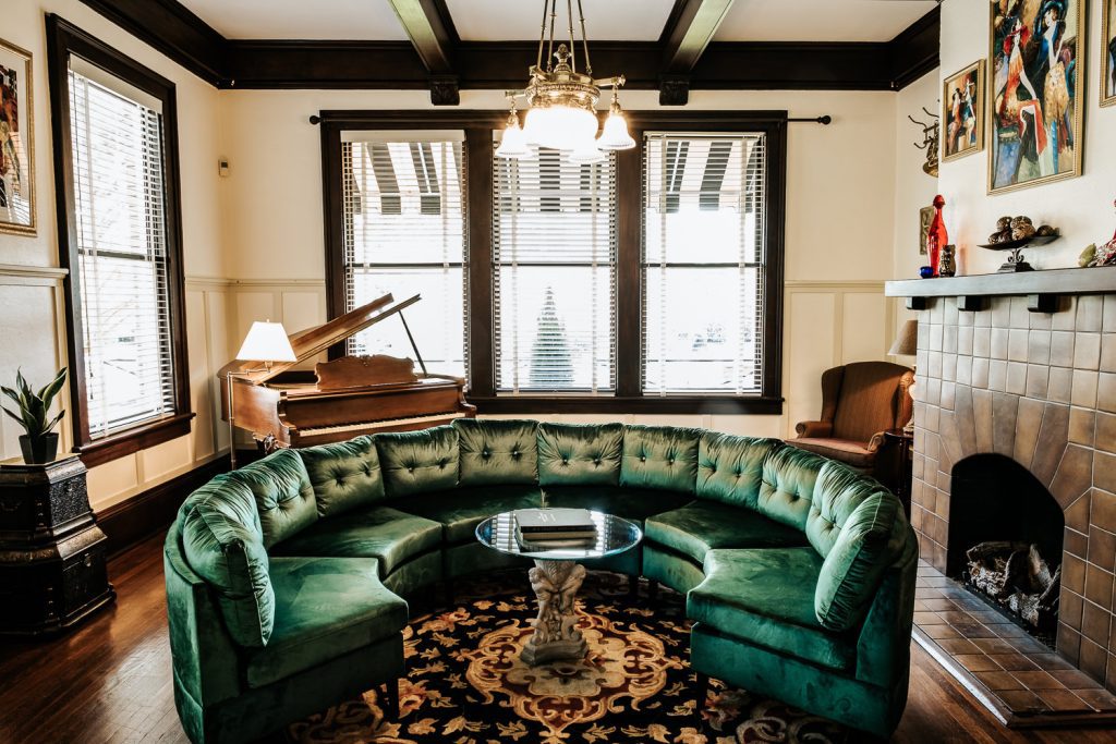 Heritage House music room featuring original art, gas log fireplace, baby grand piano, and circular couch