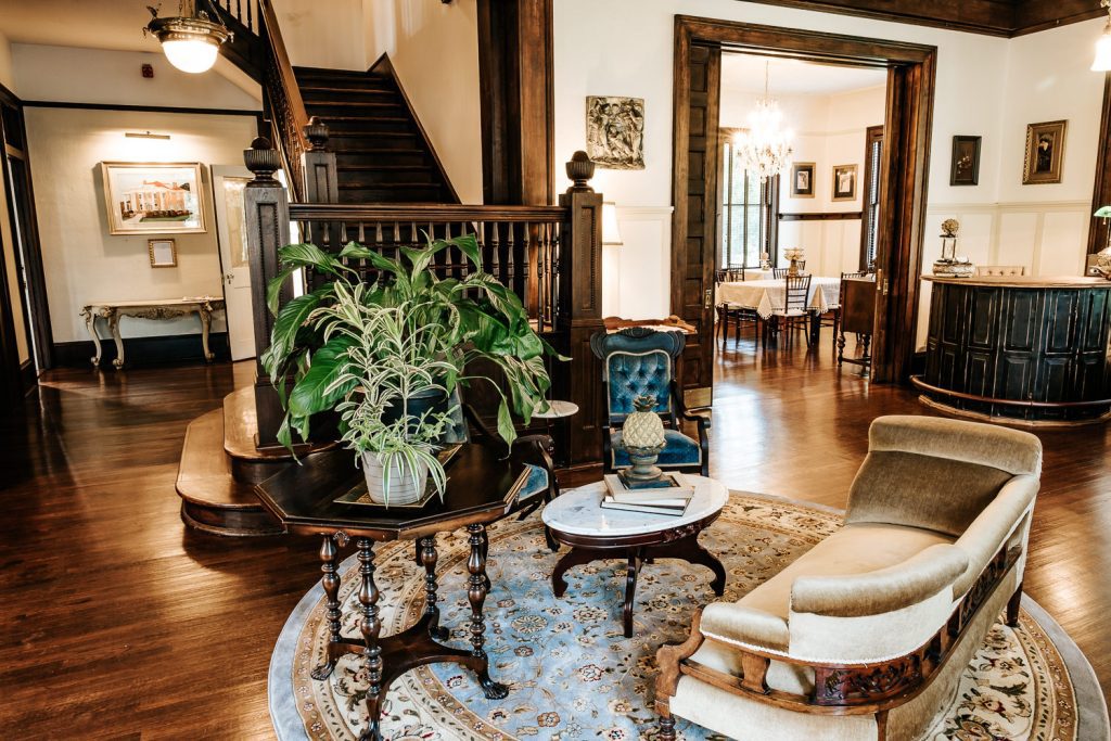 Heritage House parlor showing front desk, fainting couch, and plants